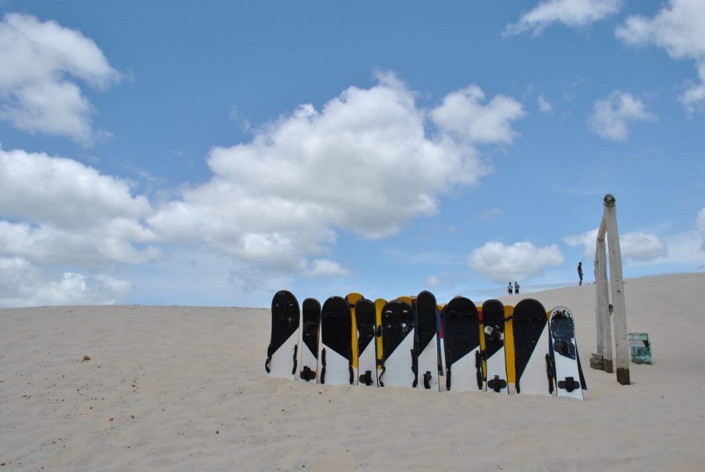 uma fileira de pranchas ski enterradas pela metade na areia 