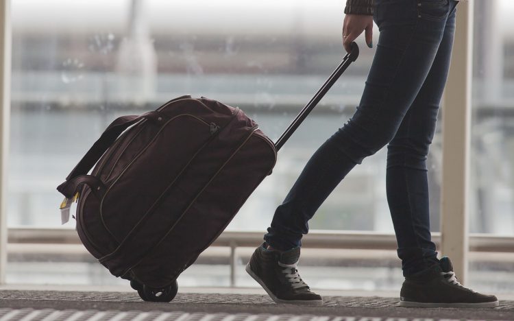 uma mulher puxando uma mala atrás dela em um aeroporto