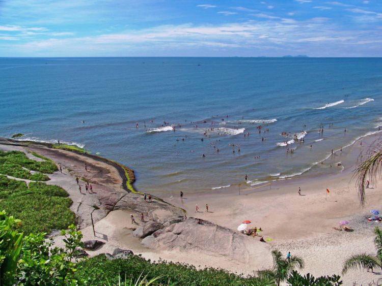 um grupo de pessoas em pé no topo de uma praia arenosa