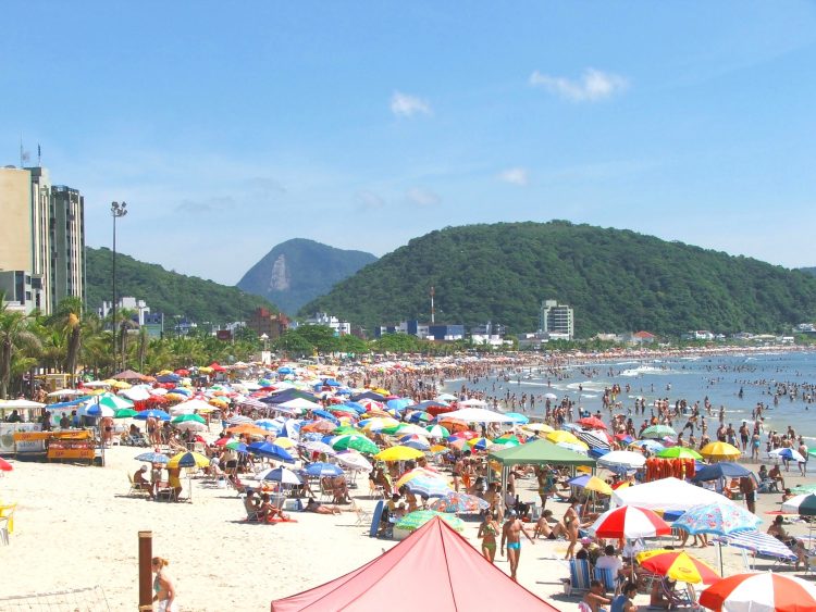 uma praia cheia de gente e guarda-sóis