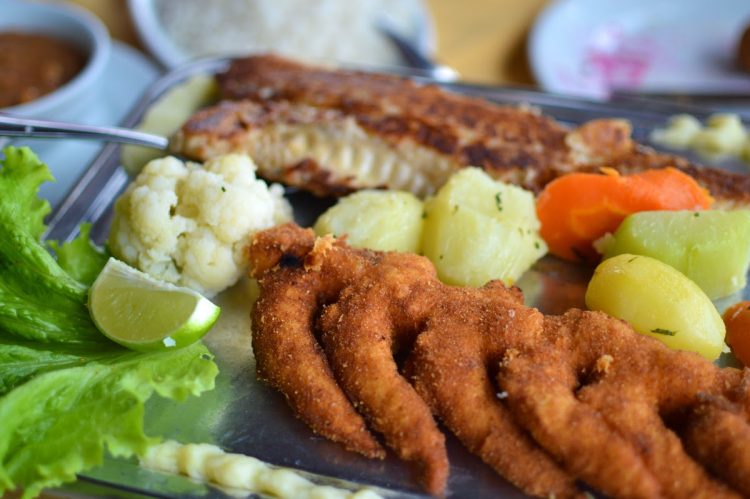 um prato de comida com legumes e cortes de peixe frito