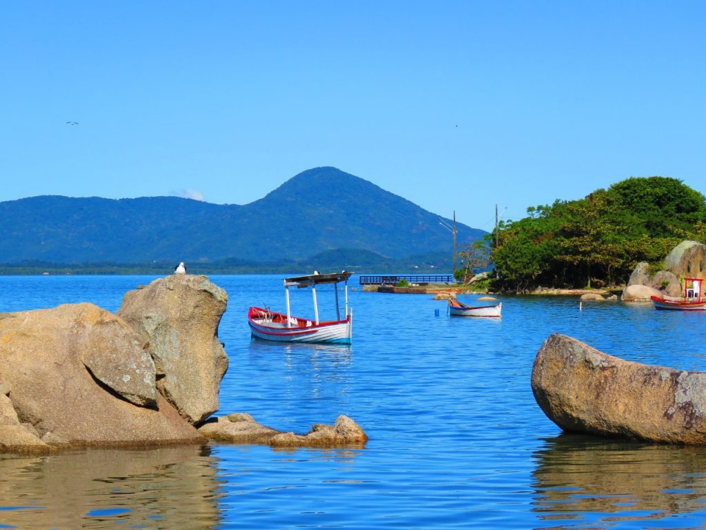 um grupo de barcos flutuando em cima de um corpo de água próximos a algumas pedras