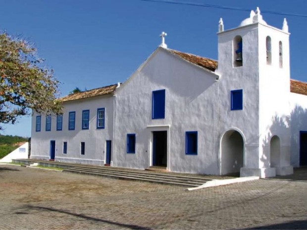 uma igreja branca com janelas azuis e um campanário