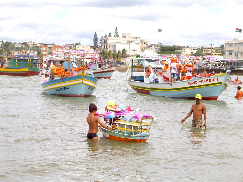 um grupo de pessoas paradas na água ao lado de barcos