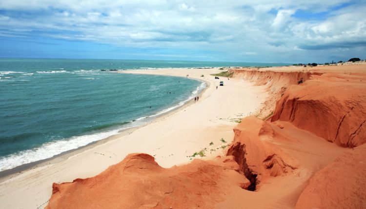 uma praia arenosa com pessoas andando nela