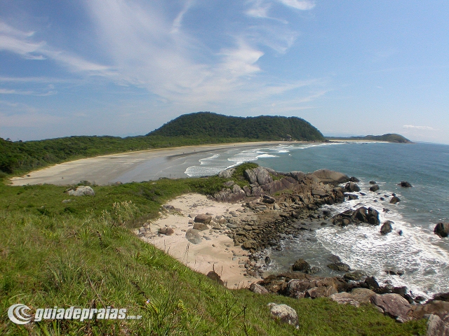 uma praia com costa rochosa e grama verde