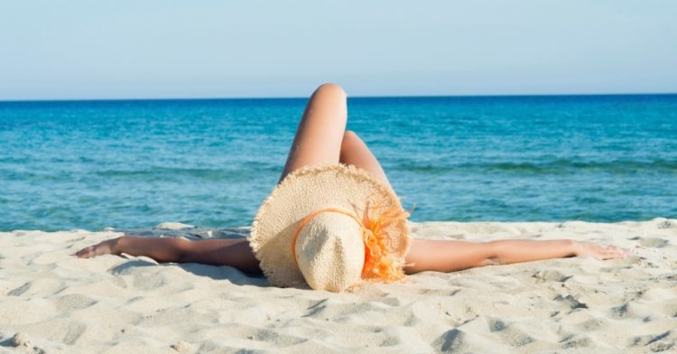 uma mulher deitada na areia da praia