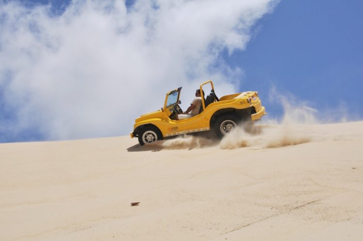 um buggy ​​amarelo descendo uma colina arenosa