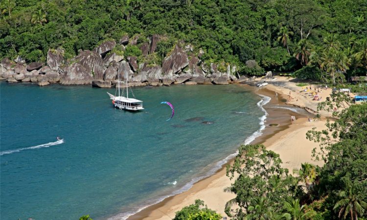 um barco que está parado na água em  frente a uma praia 