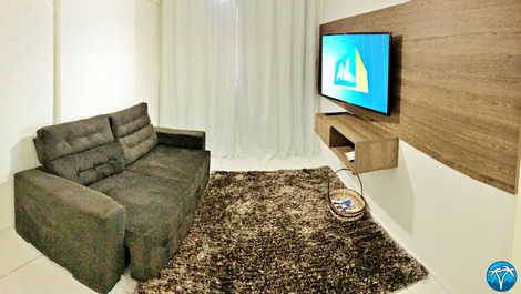 Sala de estar espaçosa com sofá retrátil e smart tv.