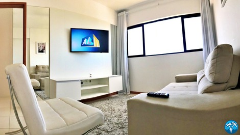 Sala de estar espaçosa com sofá retrátil e smart tv.