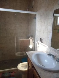 Banheiro da suite com armário, espelho e box  blindex